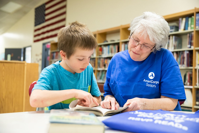 Photo of a volunteer tutoring a child at a public school to help improve reading skills.